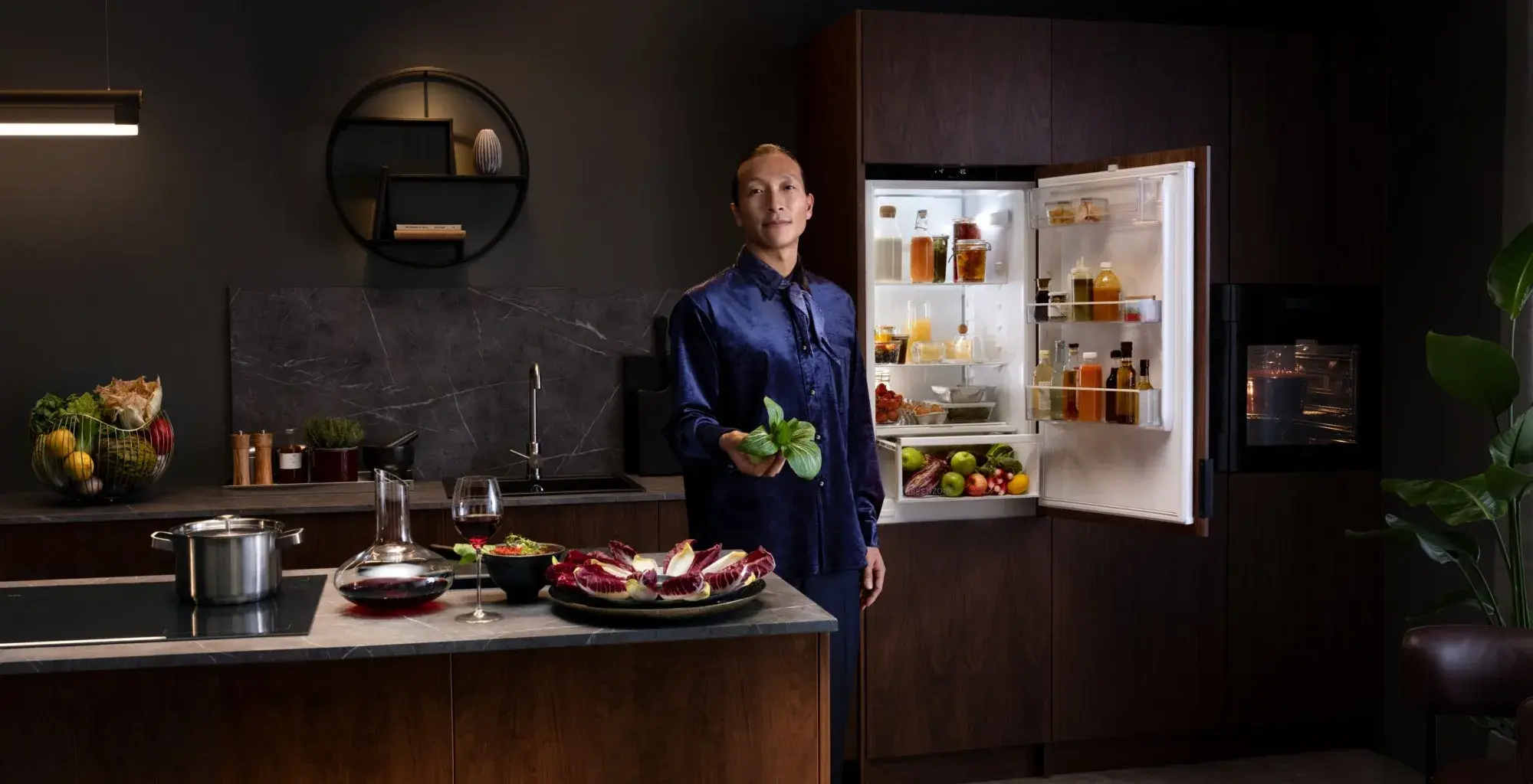 AEG Markenseite neu Header Kühlen BI_Serie 7000 geöffneter Kühlschrank davor Asiate mit Pak Choi in der Hand